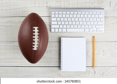 Fantasy Football Draft Still Life. A Computer Keyboard, Pad And Pencil And An American Style Football On A White Wood Table In A Home Office.