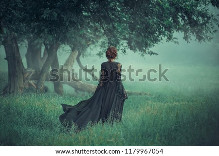 fantasy ghost girl walk dark nature forest long black vintage dress train waving fly wind. Art Gothic queen witch.  trees fog. artwork mysterious silhouette beautiful young woman medieval silk clothes