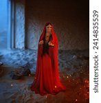 Fantasy girl Mystery arabic woman in red long dress stands in desert long silk abaya dress. clothes gold Golden Mask chain Burka hide face Oriental fashion Eastern style. Sand dunes night room fire.