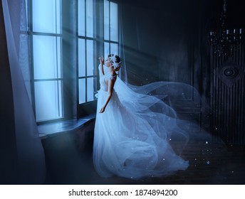 Fantasy gothic woman ghost bride stands by window in black dark room, magic moon light. Fairy snow queen in white dress, cape flying in wind, train skirt fluttering motion. Medieval vintage princess.