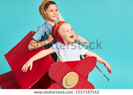 Fantasy, imagination of children. Two happy kids sit inside of cardboard red airplane imagine flight in sky. Big dream to be pilot