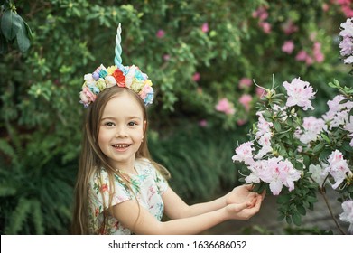 Fantasy little girl with rainbow unicorn horn with flowers in azalea park. for Halloween