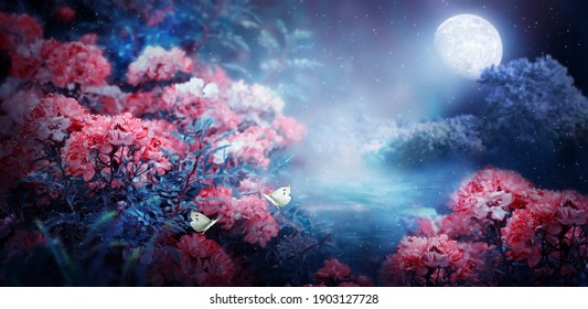 Fantasy magical enchanted fairy tale landscape with forest lake, fabulous fairytale blooming pink rose flower garden and two butterflies on mysterious blue background and glowing moon ray in night