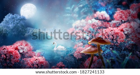 Fantasy magical enchanted fairy tale landscape with swan swimming in lake, fabulous fairytale blooming pink rose flower garden and mushrooms on mysterious blue background and glowing moon ray in night
