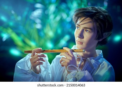 Fantasy. Portrait Of An Elf Boy Playing His Flute In The Magic Forest. Fairy Tale, Magic.