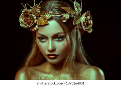 Fantasy portrait of woman with golden skin. Girl goddess in wreath, gold roses, accessories. Beautiful face, steel glitter makeup. Artistic photo, black background. Elf fairy princess. Fashion model