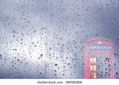 Fantasy Rain Drop On Glass Window With Blur English Red Telephone Box In England UK.