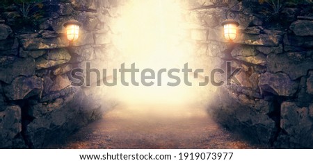 Fantasy stone dungeon cave with glowing lanterns on walls, lamp illuminate magical trail leading out from old ancient cavern towards mystical glow, scene with abandoned ruins, empty road and tunnel.