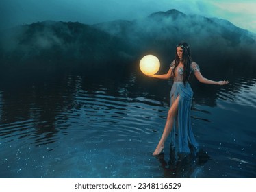 Fantasy woman holding moon magic light glowing planet in hand. Sexy Girl goddess night elf beauty face blacl long hair, river nymph wet blue dress, stands on water dark sky clouds lake. Lady fairy art