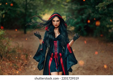 Fantasy Woman Witch Creates Magic Hands Raised Long Hair Flying In Wind Motion. Sexy Face Dark Eyes Look At Camera. Summer Nature Green Forest Trees. Gothic Girl Art Black Red Dress Old Vintage Style