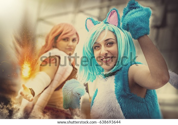 Fantasy world.\
Disguised cosplay women. Two imaginative characters of the\
fictional world. A young girl dressed as a cat and another girl\
with a hand that generates a\
fire.
