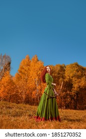 Fantasy world. Full length portrait of a beautiful red-haired girl archer of the Middle Ages stands on a meadow. Celtic culture. Autumn nature.