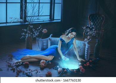 Fantasy young beautiful sorceress woman. long blue dress touch divine old mirror. Predictor future fairy tale Snow White. magic power wind light spell. Mystic gothic art photo dark black medieval room