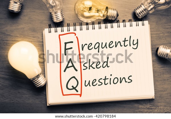 FAQ ( frequently asked questions ) text on notebook\
with many light bulbs