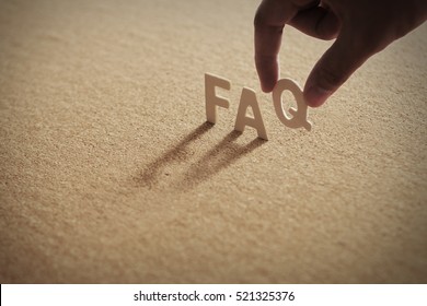 FAQ-Holzwort auf komprimiertem Brett, Kork-Brett mit menschlichem Finger auf Q-Brief