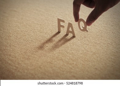 FAQ-Wort auf komprimierter Tafel mit menschlichem Finger auf Q-Brief