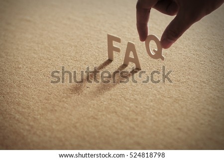 FAQ word on compressed board with human's finger at Q letter