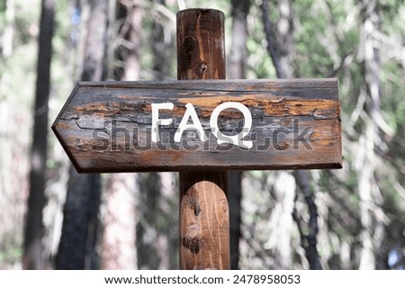 FAQ words. Question and Answer concept. FAQ written on a piece of a wooden pole against the background of a forest