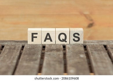 Faqs concept with wooden block on wooden table background.