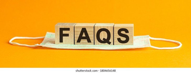 Faqs Word Written On Wood Block. Faqs Text On Table, Concept. Wooden Block With Words FAQS On Wooden Cubes, With The Medical Mask , Health Concept, Yellow Background.