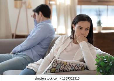 Too far from one another. Nervous angry young couple sitting on opposite sides of sofa keeping silence after quarrel argument fight, feeling offended upset with each other, avoid talking communicating
