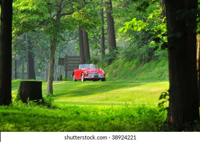 A Far View Of A Red Convertible Classic Sports Car On The Open Country Side Road