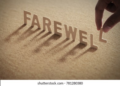 FAREWELL wood word on compressed or corkboard with human's finger at L letter.