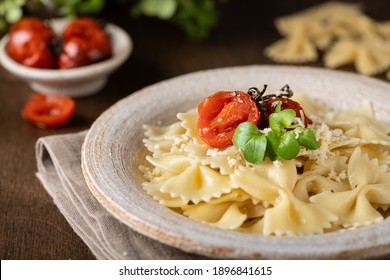 Farfalle pasta in a ceramic plate on a wooden background, selective focus
