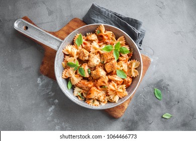 Farfalle Pasta In Tomato Sauce With Chicken,  Basil In Pan. Chicken Italian Bow Tie Pasta Over Concrete Background With Copy Space, Homemade Italian Food.