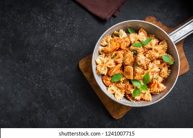 Farfalle Pasta In Tomato Sauce With Chicken,  Basil In Pan. Chicken Italian Bow Tie Pasta Over Black Background With Copy Space, Homemade Italian Food.