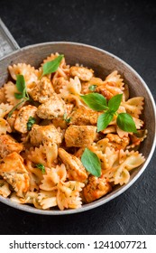 Farfalle Pasta In Tomato Sauce With Chicken,  Basil In Pan. Chicken Italian Bow Tie Pasta Over Black Background With Copy Space, Homemade Italian Food.