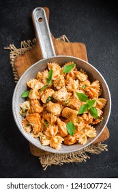 Farfalle Pasta In Tomato Sauce With Chicken,  Basil In Pan. Chicken Italian Bow Tie Pasta Over Black Background With Copy Space, Homemade Italian Food.