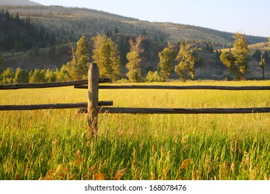 Farm Fence And Green Fields At Sunset