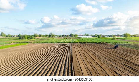 Farm field landscape and a tractor. Agricultural industry. Development of agricultural economy. Farming, agriculture. Preparing for a new planting. Loosening surface, land cultivation.