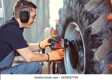 Farm machine mechanic working on wheel with power tool - Powered by Shutterstock