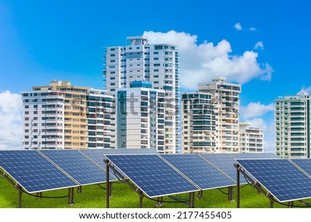 Farm with solar panels. Solar panels to supply electricity to houses. Green power plant in front of high-rise buildings. Eco friendly electricity generator. Innovative solar panels in front of city