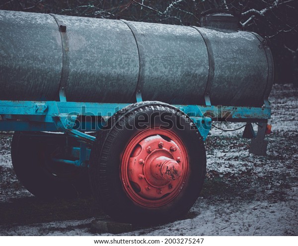 A farm tractor\
trailer with a red wheel