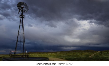 A Farm Windmill In The Field Under A Foggy Sky