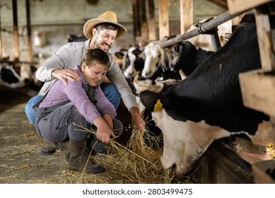 Farmer and boy bonding while working on a dairy farm, feeding livestock, learning about agriculture and traditions