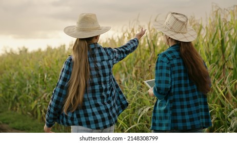 Farmer Businessman Talking In Cornfield, Making Deal, Using Computer Tablet. Growing Food. Partner. Two Farmers Women With Digital Planets Working Together In Corn Field. Agricultural Business Concept