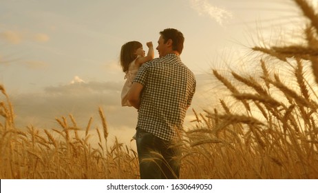 farmer carries little daughter in his arms through a field of wheat. happy child and father are playing in field of ripening wheat. baby boy and dad travel on field. kid and parent play in nature. - Powered by Shutterstock