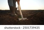 The farmer is digging the field with shovel. garden soil dig concept. a farmer digs the soil with a shovel into the ground with his feet. a lifestyle farmer with his legs shoveling a field.