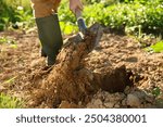 Farmer digging soil with shovel on sunny day, closeup