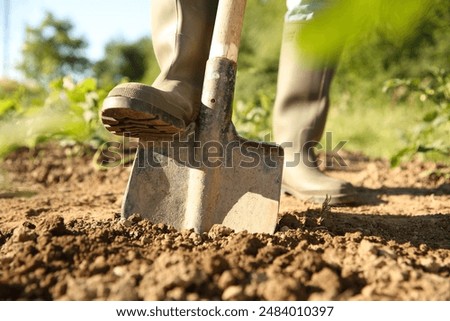 Farmer digging soil with shovel on sunny day, closeup