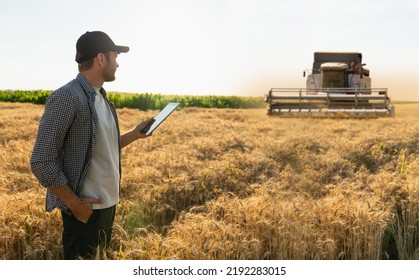 Farmer with digital tablet on a background of combine harvester. Smart farming concept. - Shutterstock ID 2192283015