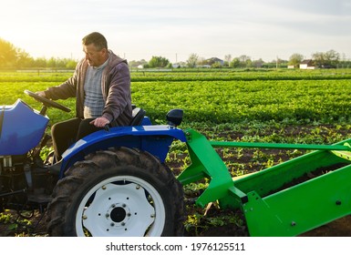 Farmer drives tractor across farm field. Harvest first potatoes in early spring. Farming and farmland. Agro industry and agribusiness. Harvesting mechanization in developing countries. Farms support - Shutterstock ID 1976125511