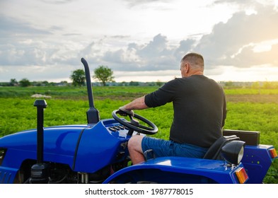 Farmer drives a tractor. Harvesting crops campaign, earthworks. Agroindustry and agribusiness. Countryside farmland. Farming. Agricultural machinery management. - Shutterstock ID 1987778015