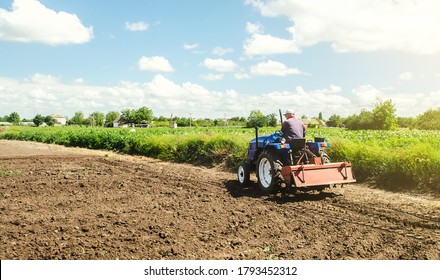 Farmer drives a tractor with a milling machine. Loosening surface, cultivating the land. Farming, agriculture. Loosens, grind and mix soil on plantation field. Field preparation for new crop planting. - Shutterstock ID 1793452312