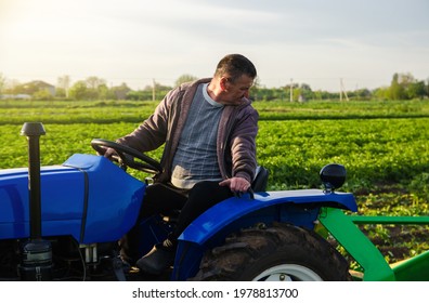 A farmer drives a tractor while harvesting potatoes. First potato harvest in early spring. Agro industry and agribusiness. Harvesting mechanization in developing countries. Farming and farmland. - Shutterstock ID 1978813700