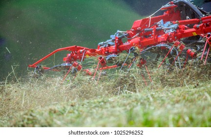 A farmer is driving his tractor and the rotary rakes are turning hay around.